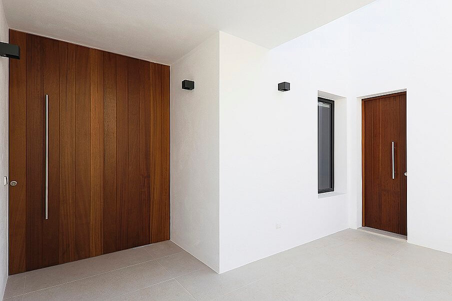 Puertas de entrada de madera maciza con tirador vertical en vivienda de diseño contemporáneo en Can Yola, Ibiza