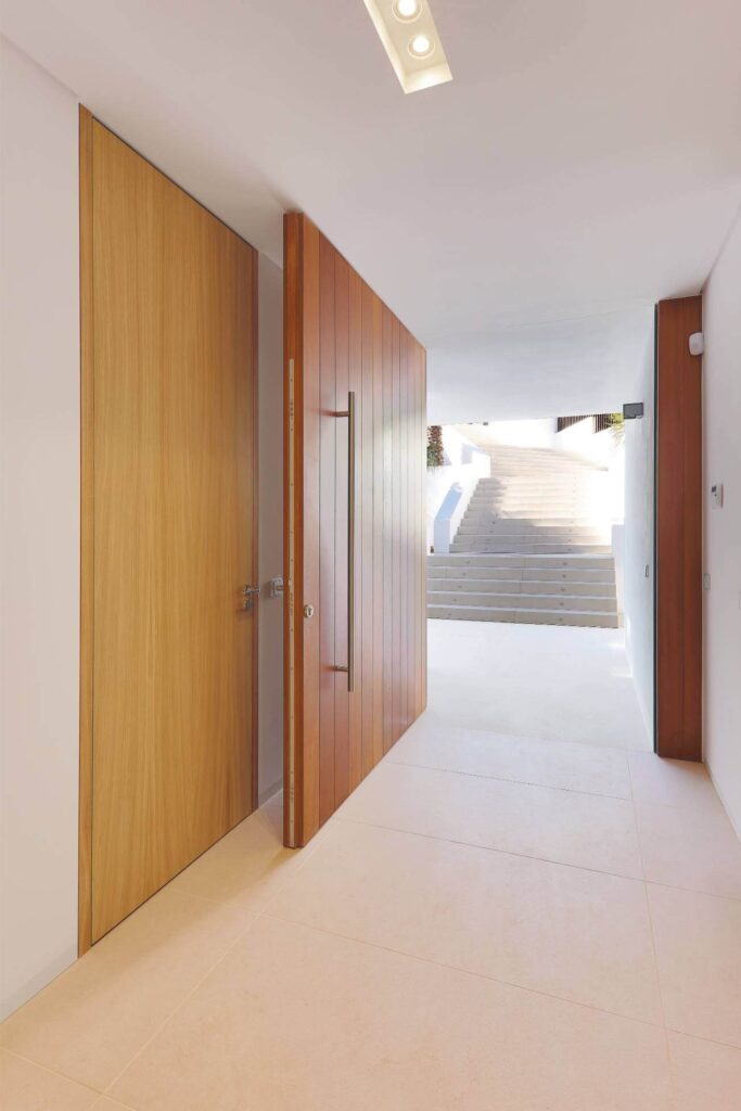 Puerta pivotante de entrada fabricada en madera con tirador vertical