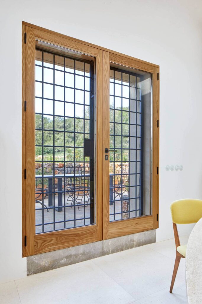 Ventana oscilobatiente con marco de madera y reja de seguridad instalada por Carpintsa en vivienda de Ibiza