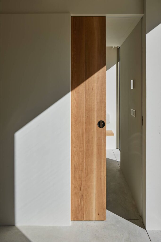 Puerta corredera de madera integrada en pared con tirador redondo
